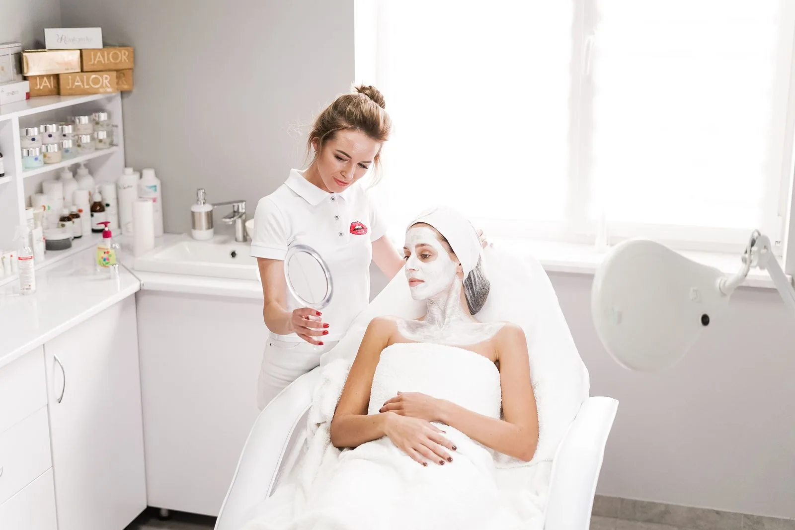 Esthetician showing facial treatment results to a client in a modern beauty clinic