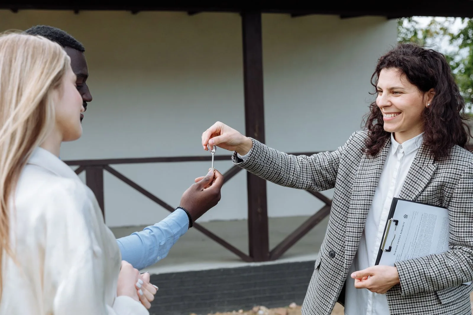 Real estate agent handing house keys to a happy couple outside their new home
