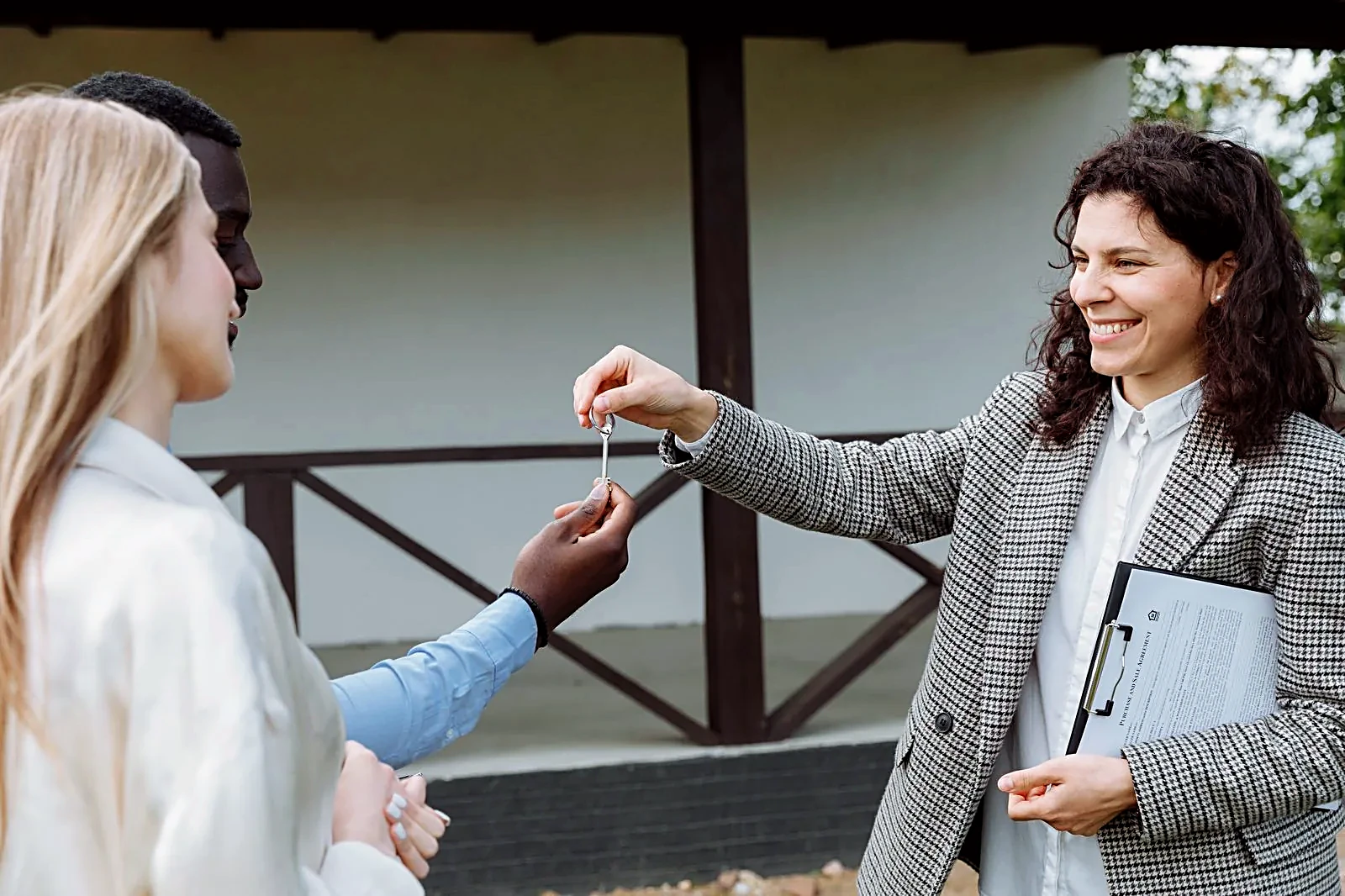 Real estate agent handing house keys to a happy couple outside their new home