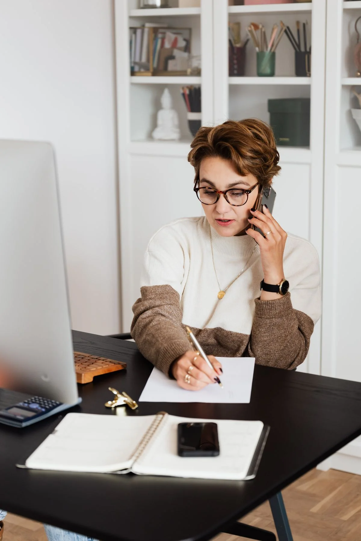 Woman on the phone taking notes at a desk