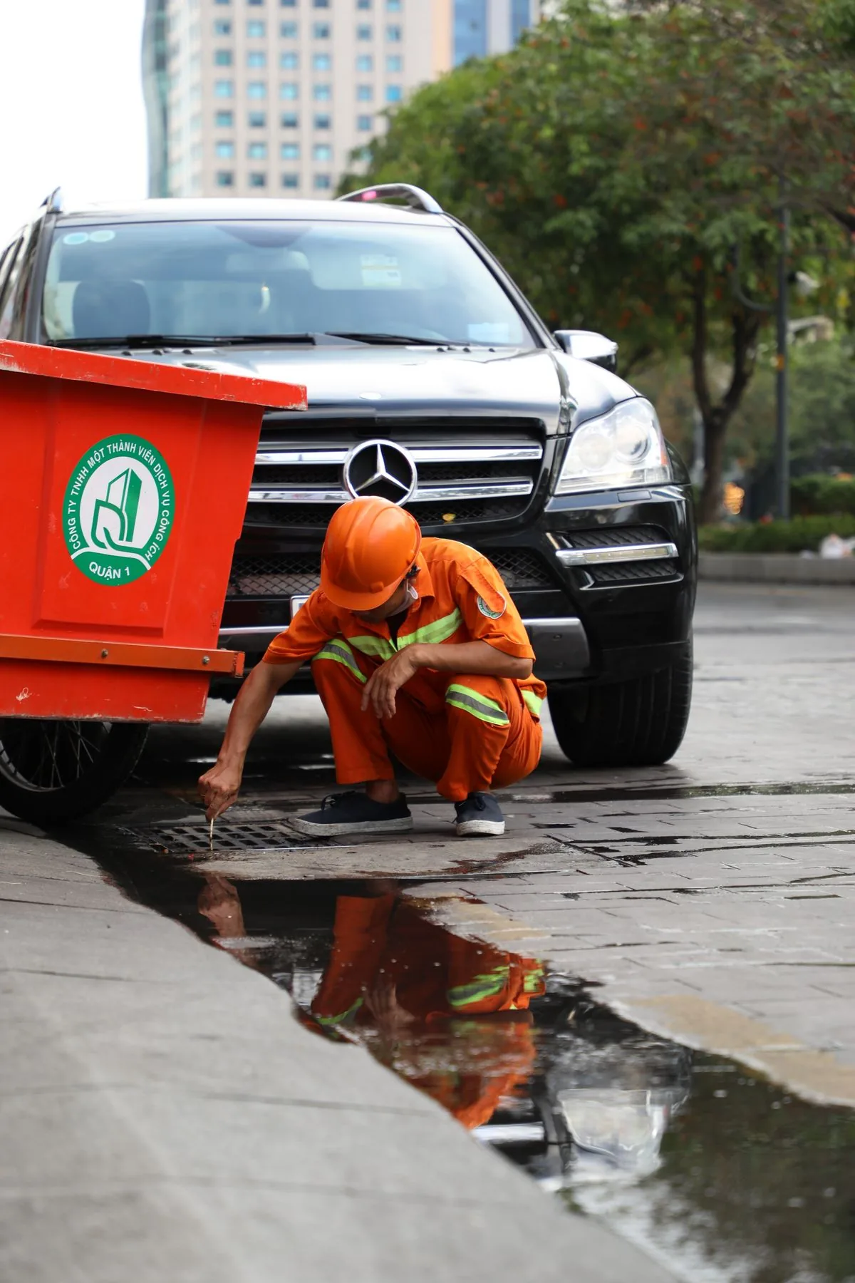 Service technician inspecting a drain beside a work vehicle