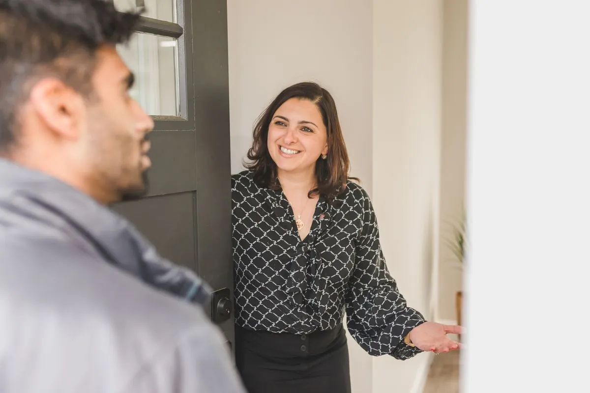 Contractor handing a printed bid document to a homeowner at the front door