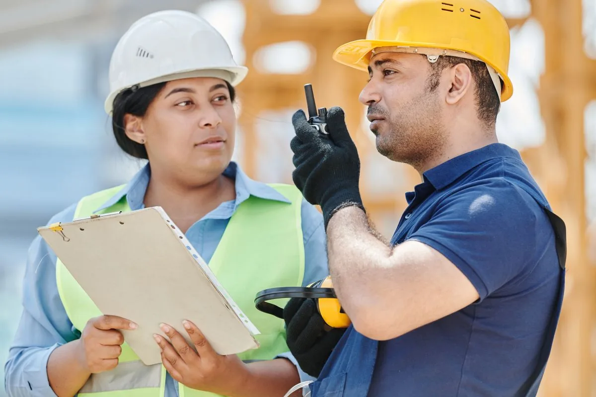 Two construction workers reviewing plans and discussing changes on site