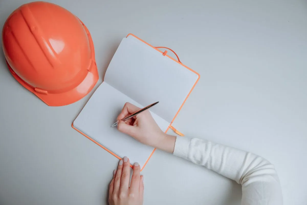 Foreman writing in a daily log notebook on an active construction site