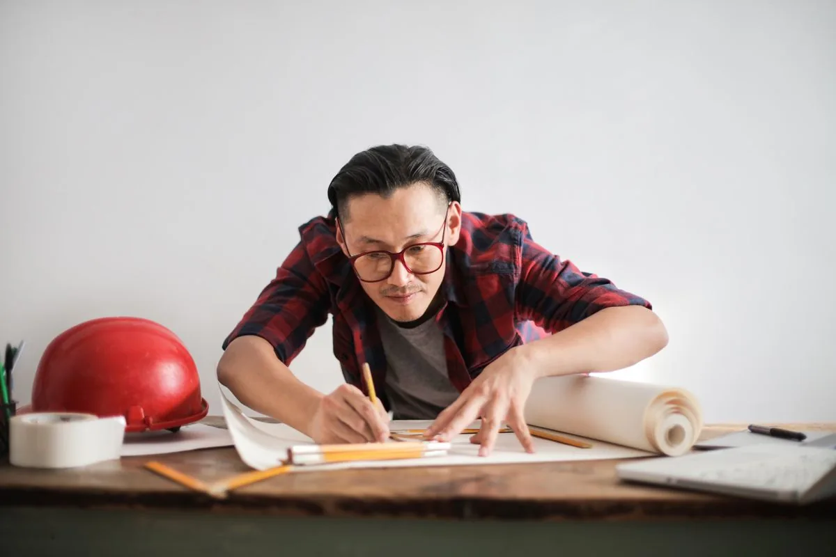 Contractor with a hard hat writing up paperwork at a desk