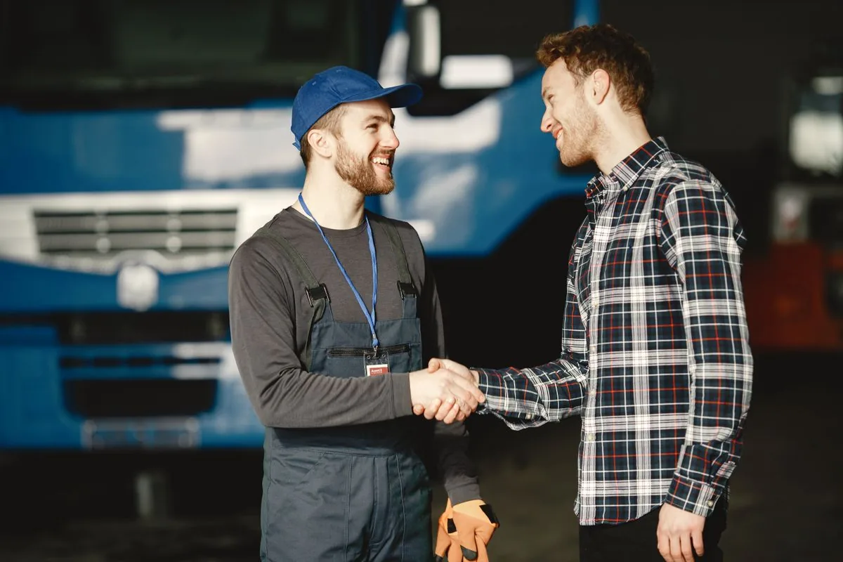 Contractor shaking hands with a customer in front of a service van