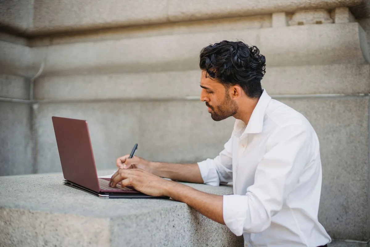 Contractor working on a laptop reviewing job numbers outdoors