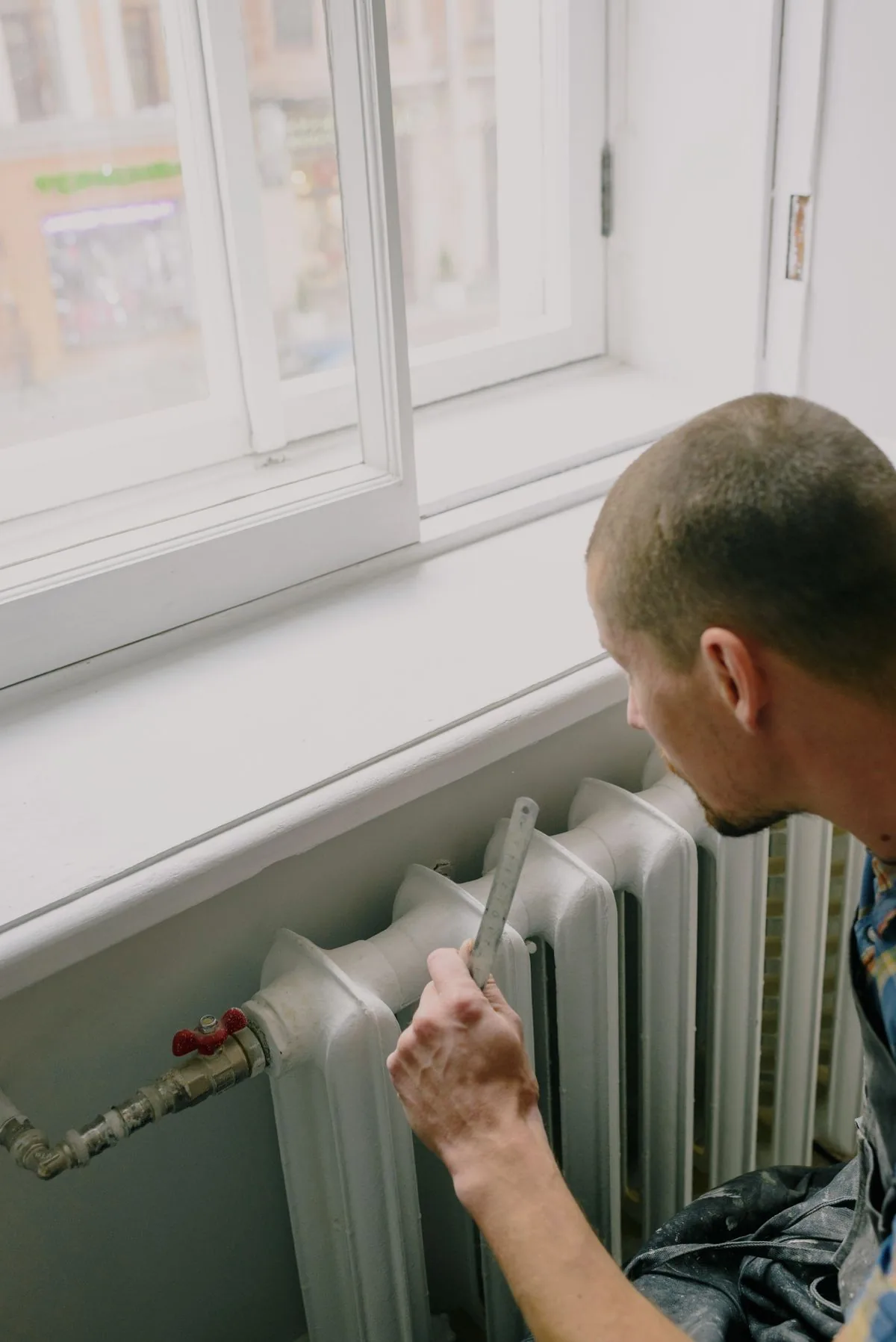 Worker measuring a radiator during a service visit