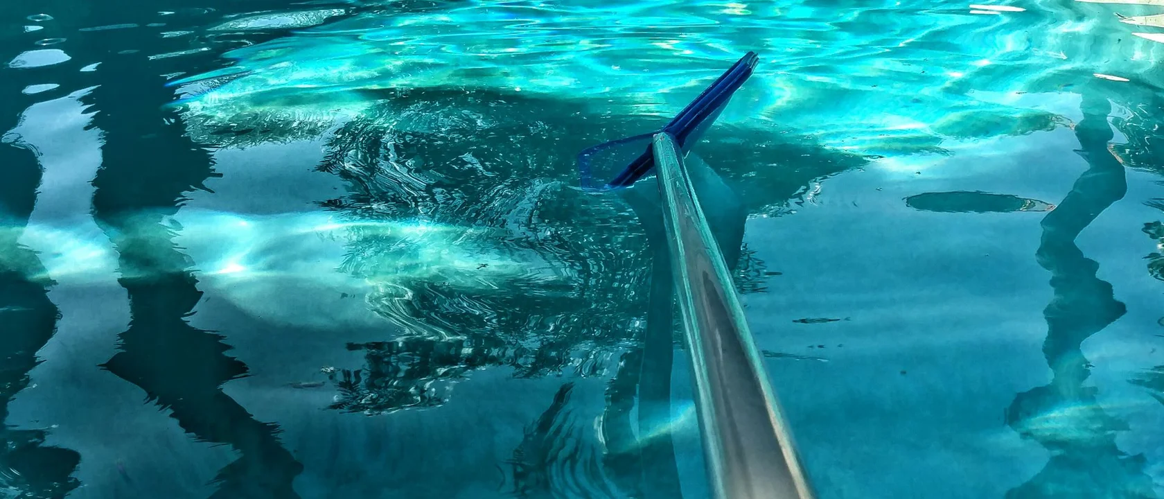 Clean residential swimming pool with skimmer net during routine service