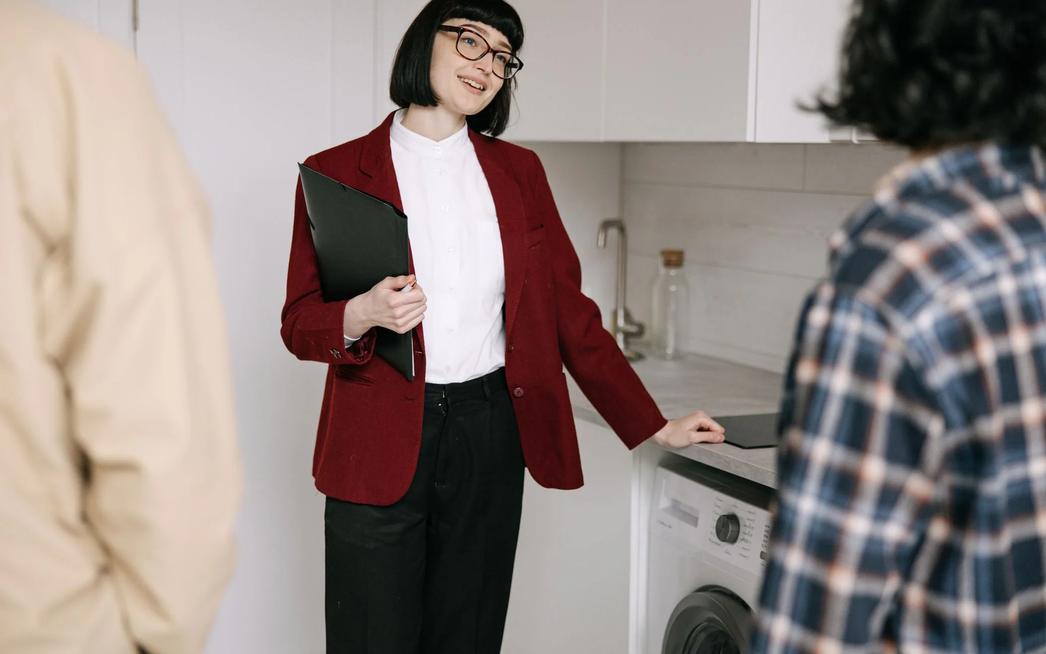 Real estate agent showing clients a modern kitchen during an apartment viewing
